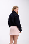 Back view of a woman wearing a navy cropped half-zip hoodie with 'STAY CLOSE' text, paired with a light pink mini skirt featuring silver star embellishments, against a plain background