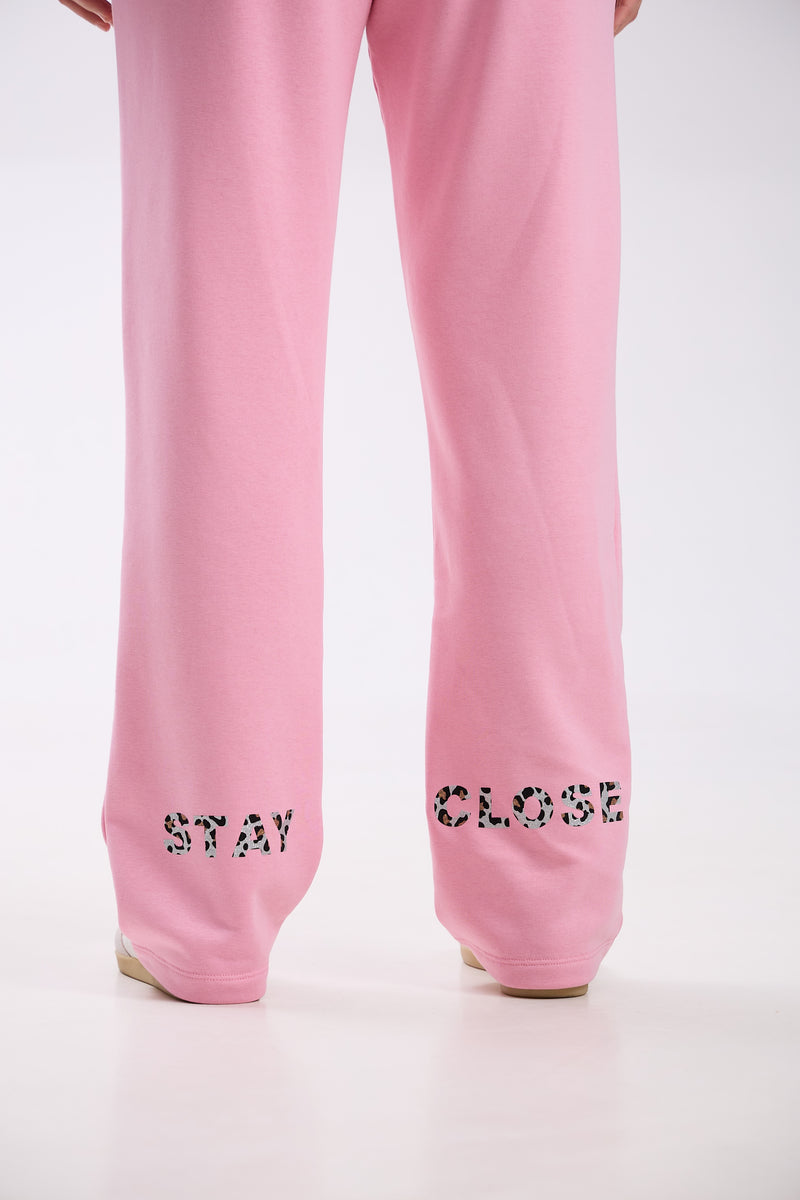 Pink straight-leg sweatpants with “Stay Close” leopard print logo detail on the back hem