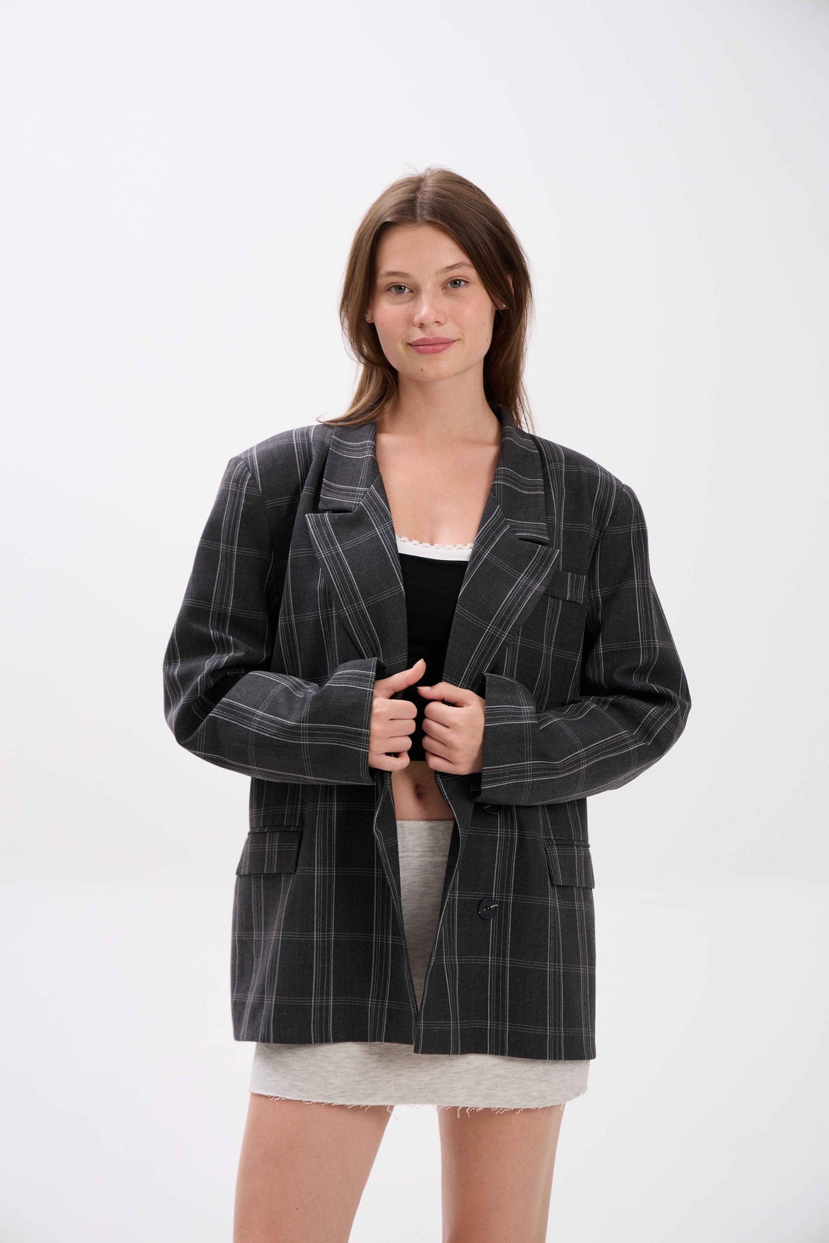 Woman wearing a black pinstripe blazer on a white background.