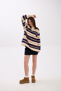 Person wearing a striped sweater and dark skirt on a white background