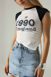 Person wearing a white and black '1990 England' t-shirt with a denim skirt.