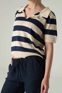 Person wearing a navy and white striped shirt with a plain background.