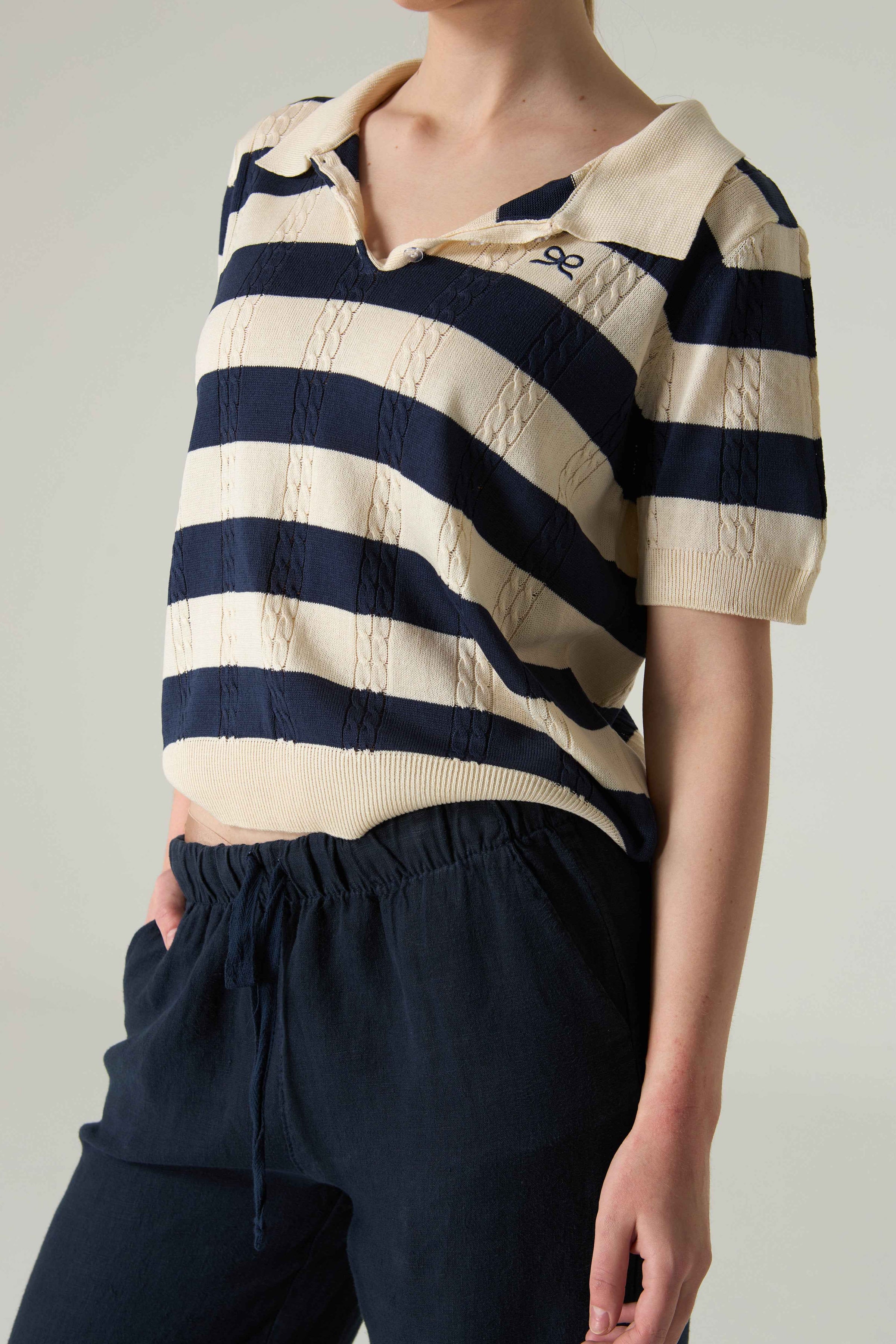 Person wearing a navy and white striped shirt with a plain background.