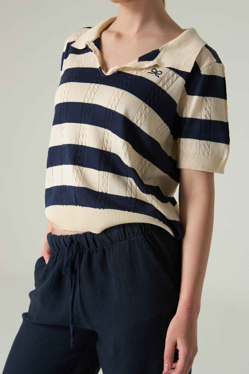 Person wearing a navy and white striped shirt with a plain background.
