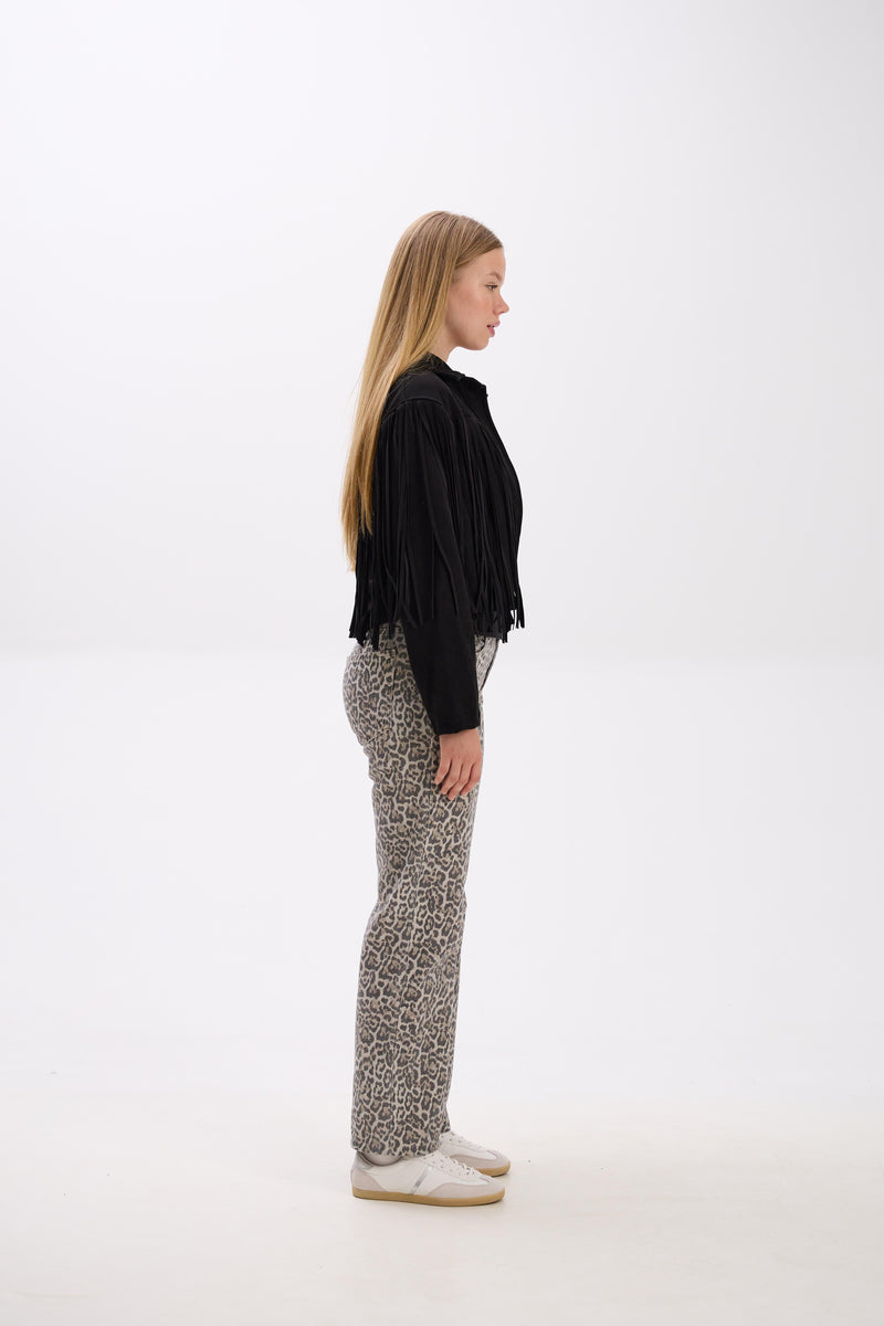 Woman wearing a black top and patterned pants on a white background.