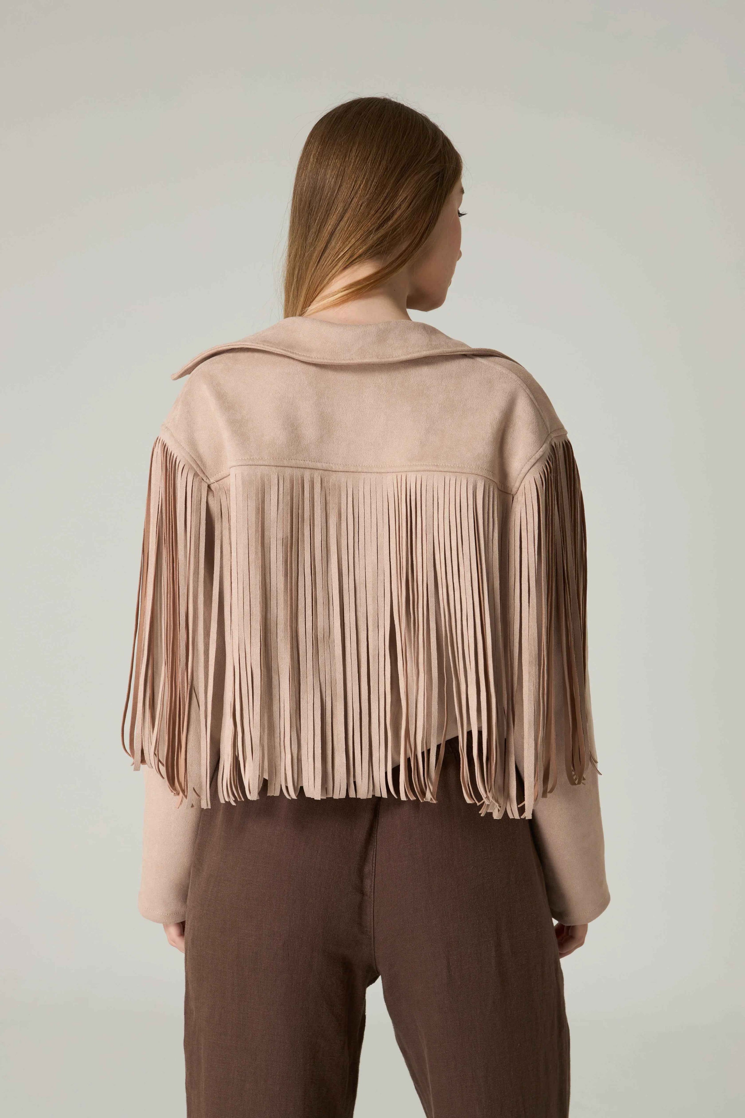 Person wearing a beige fringed jacket against a plain background.