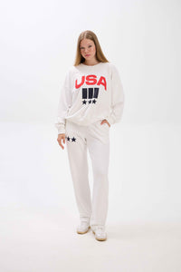 Person wearing a white sweatshirt with 'USA' print on a white background.