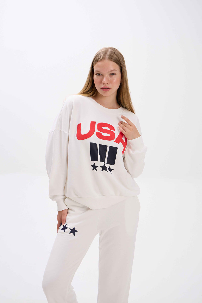 Person wearing a white sweatshirt with 'USA' text on a white background.