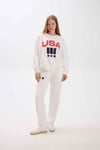 Person wearing a white sweatshirt with 'USA' text on a plain background.