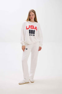 Person wearing a white sweatshirt with 'USA' text on a plain background.