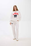 Person wearing a white sweatshirt with 'USA' print on a white background.