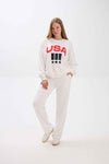 Woman wearing a white sweatshirt with 'USA' text on a white background.