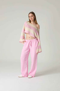 Woman wearing a pastel striped top and pink pants on a white background.