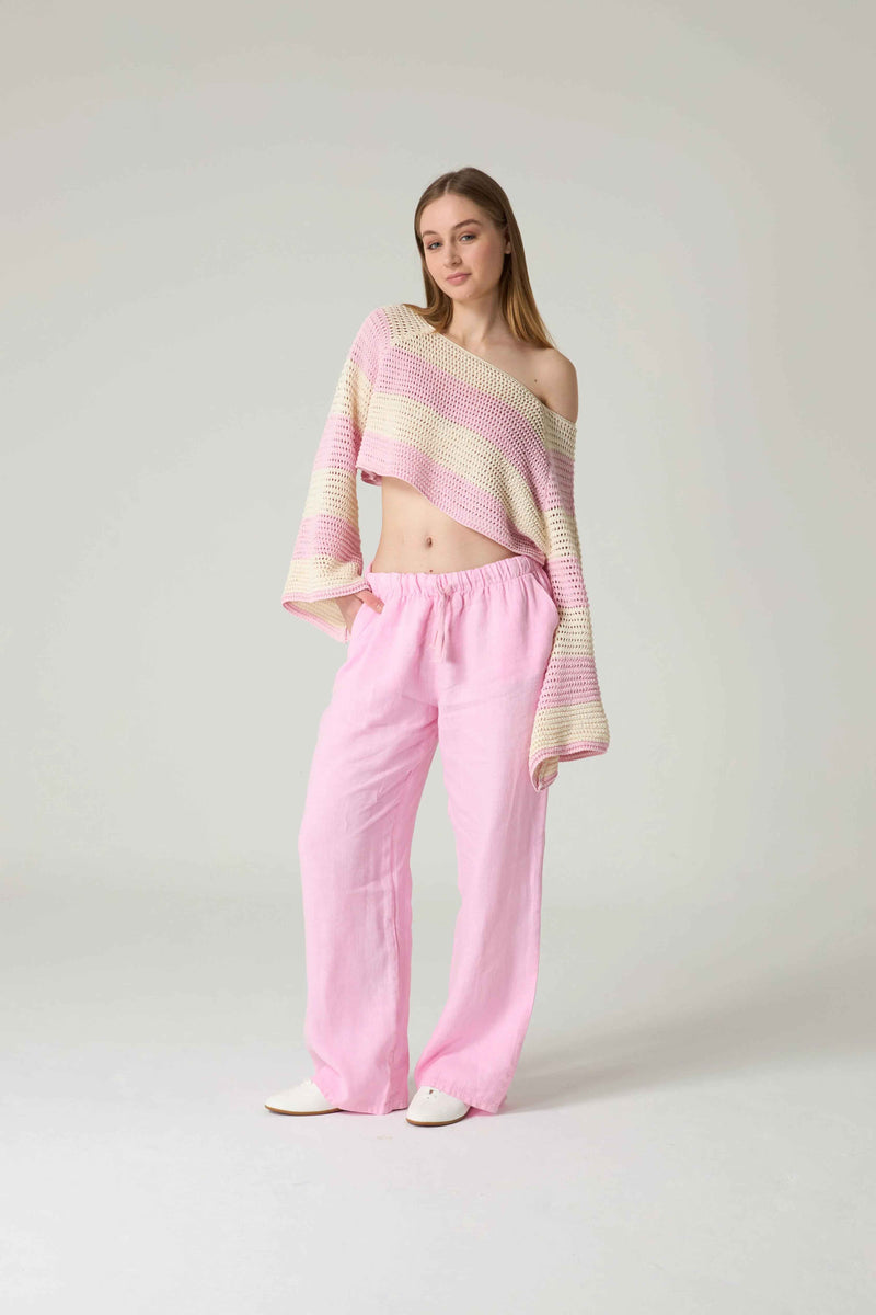 Woman wearing a pastel striped top and pink pants on a white background.