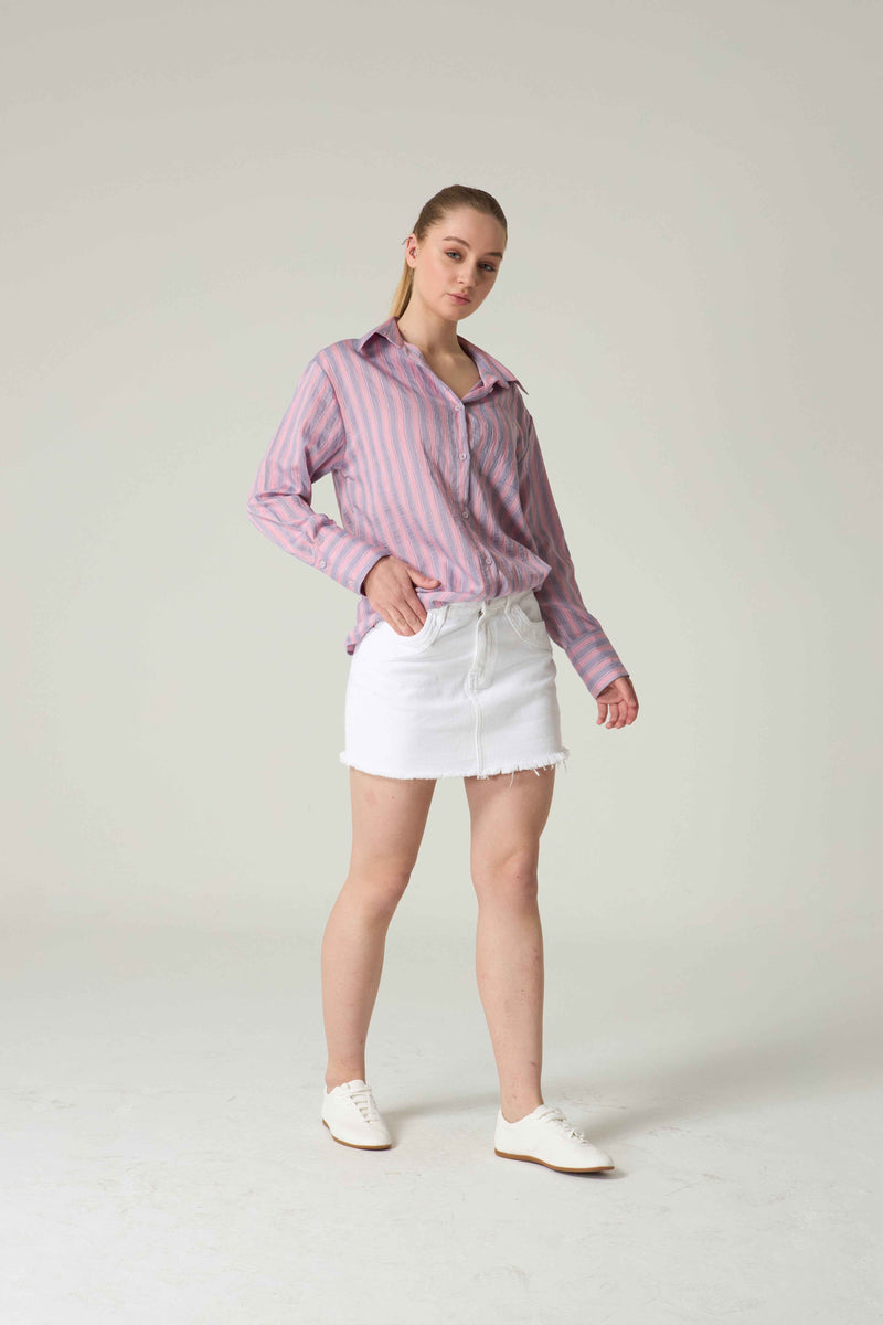 Woman wearing a pink striped shirt and white shorts on a plain background.