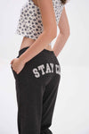 Person wearing black sweatpants with 'STAY CLOSE' text on a white background.