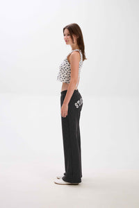 Woman wearing a patterned top and black pants with text on a white background.