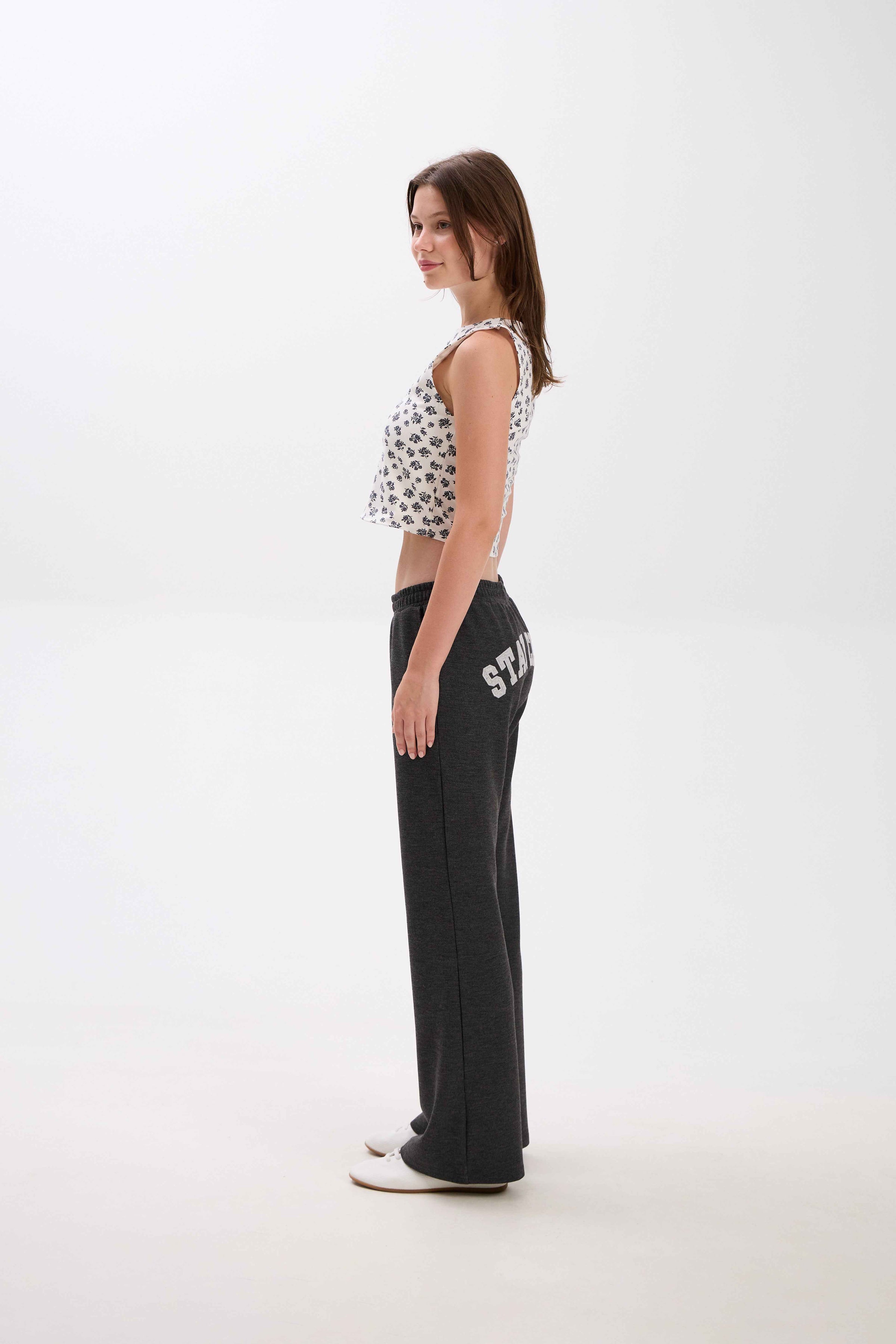Woman wearing a patterned top and black pants with text on a white background.
