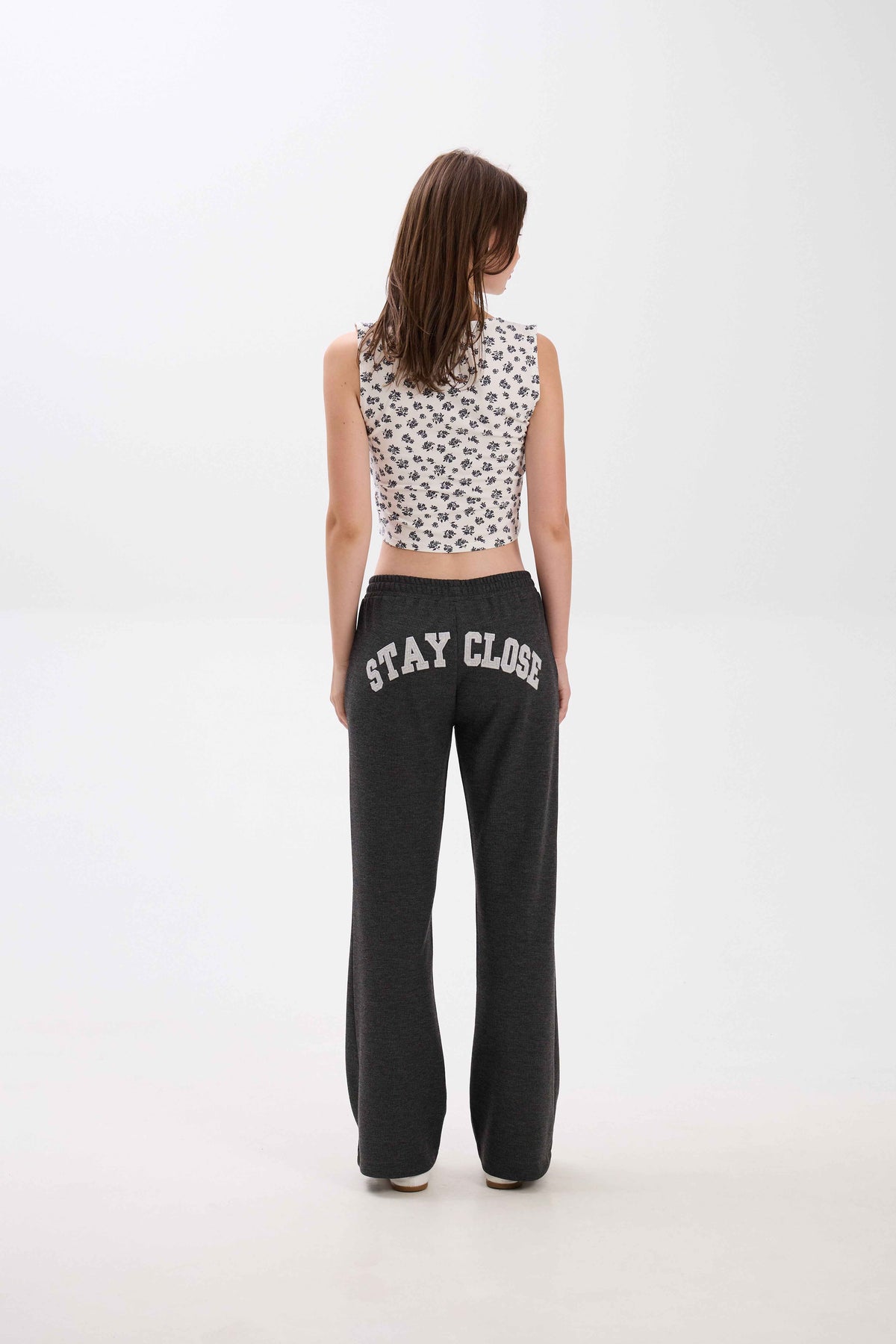 Person wearing a patterned top and black sweatpants with 'STAY CLOSE' text on a white background.