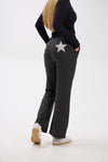 Person wearing dark gray sweatpants with a star design on a white background.