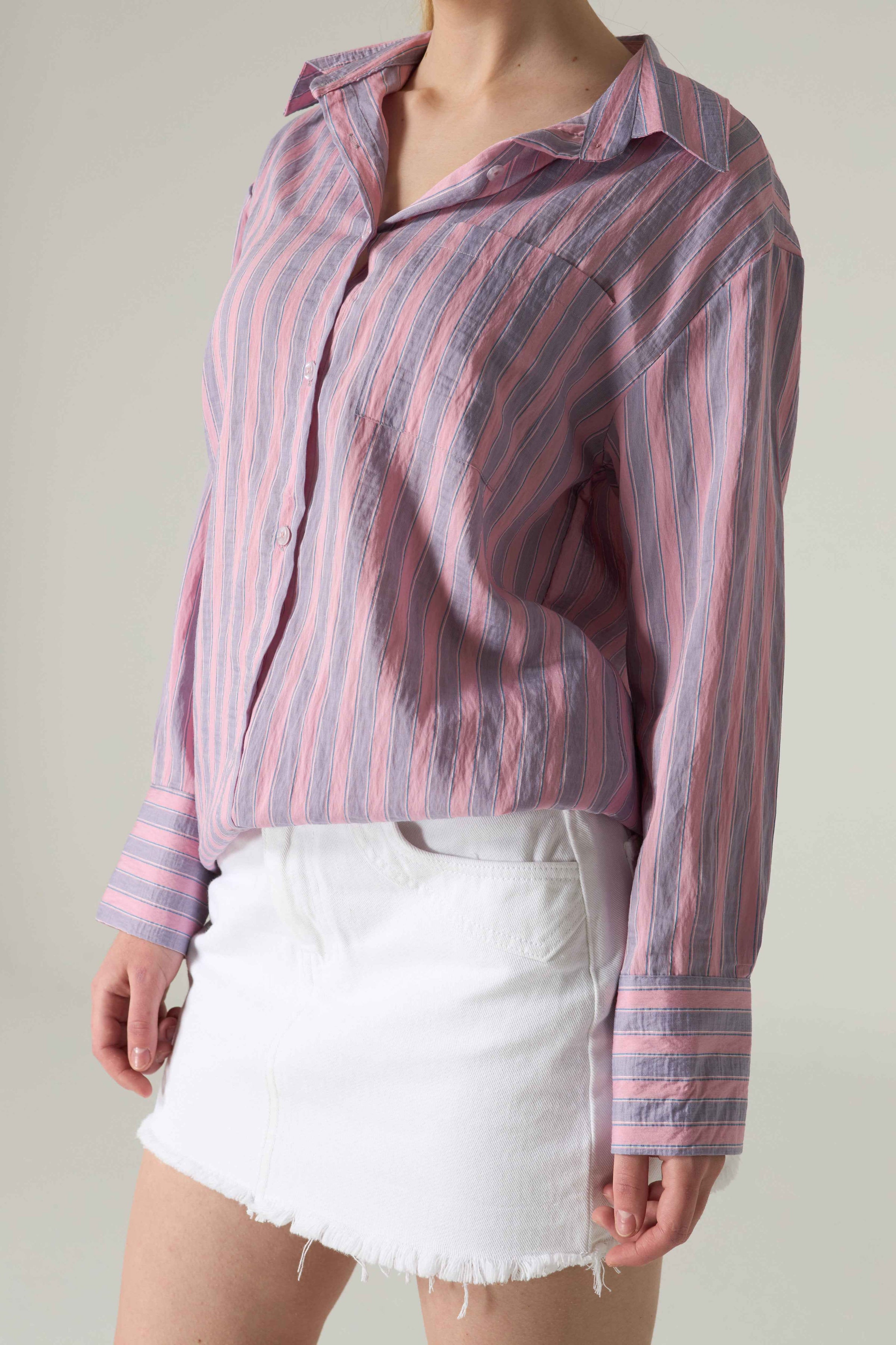 Person wearing a striped shirt and white shorts against a plain background.