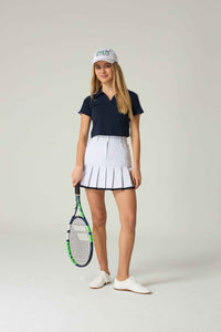 Woman in tennis attire holding a racket on a plain background.