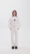 White sweatpants with elastic waistband, side pockets, and multicolor USA lettering on the back, shown in motion for a casual look.