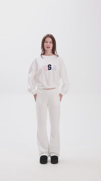 White sweatpants with elastic waistband, side pockets, and multicolor USA lettering on the back, shown in motion for a casual look.