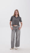 Person wearing a gray cropped polo shirt and gray jeans on a white background