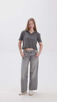 Person wearing a gray cropped polo shirt and gray jeans on a white background