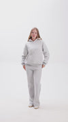 Person wearing grey sweatshirt and a matching sweatpant on a white background.