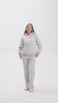 Person wearing grey sweatshirt and a matching sweatpant on a white background.