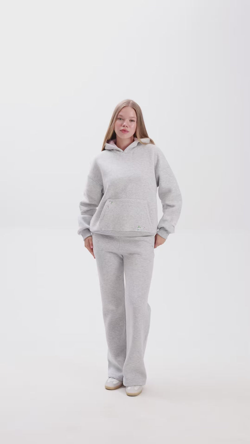 Person wearing grey sweatshirt and a matching sweatpant on a white background.