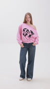 Model showcasing a pink off-shoulder sweatshirt with bold “Stay Close” print, paired with blue jeans and white sneakers.